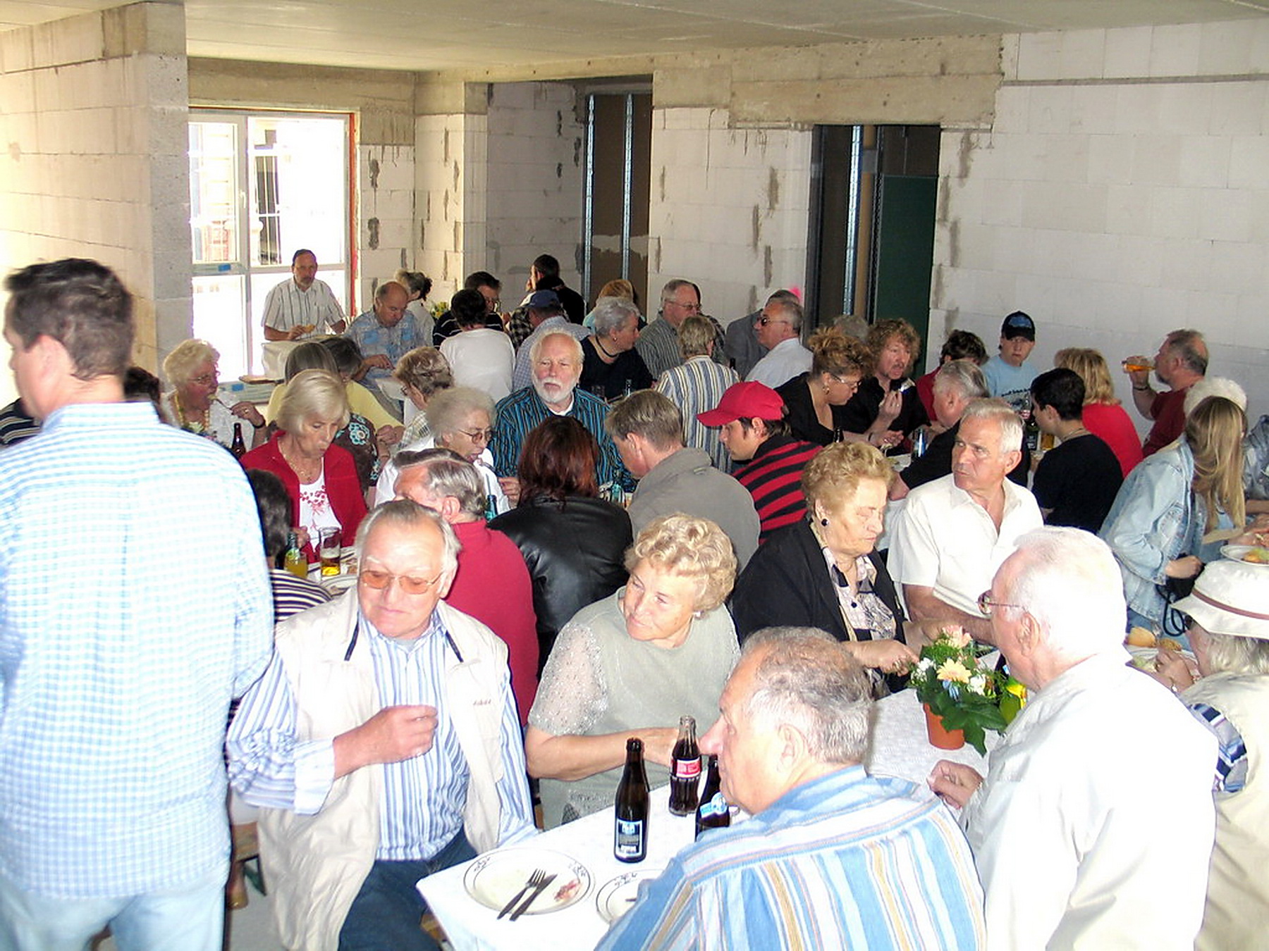 Bauleute, Handwerker, künftige Bewohner und Nachbarn feiern in den Räumen der Anlage