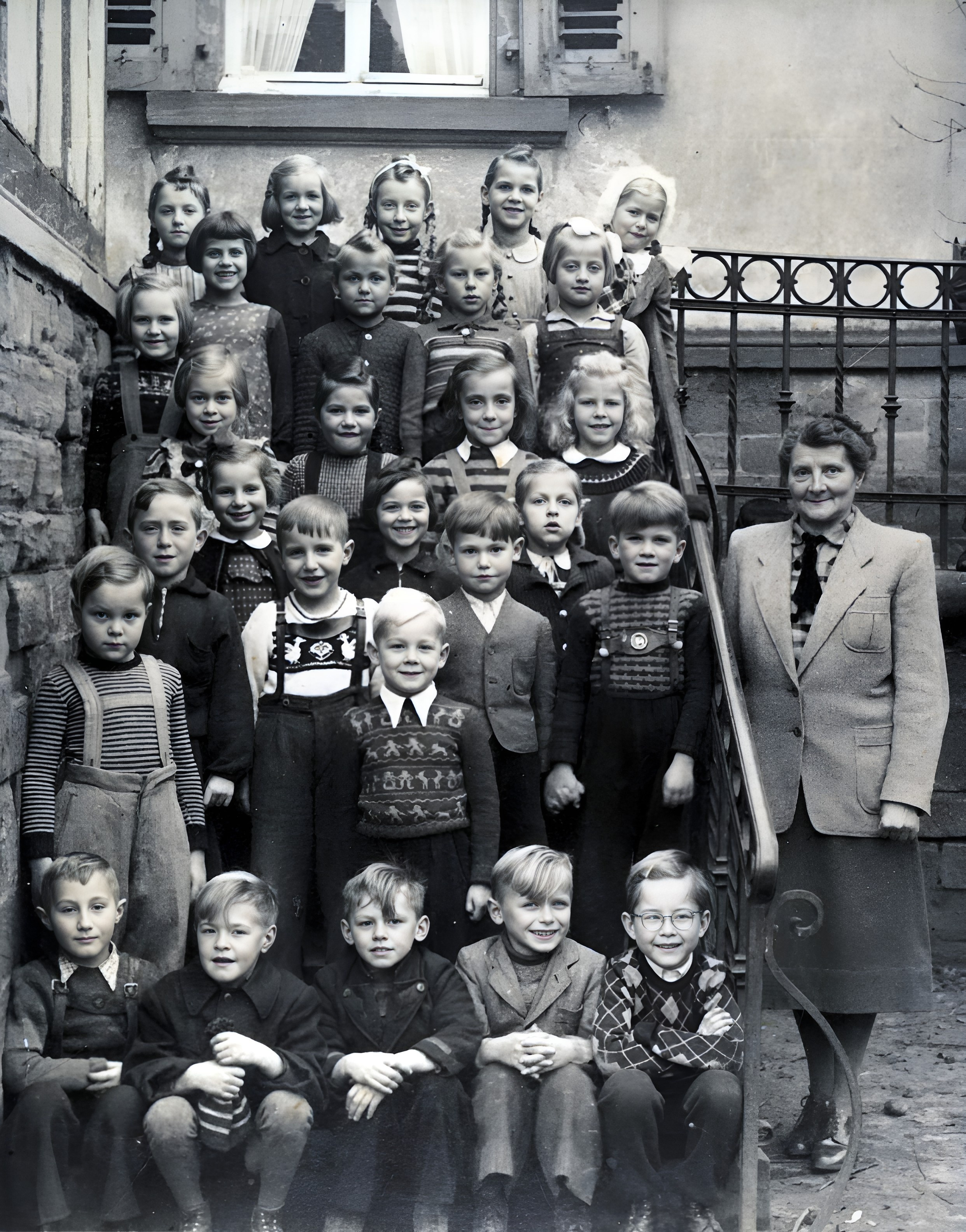 Gruppenfoto Schuljahrgang 1951/1952 (Geburtsjahrgänge um 1945)  Lehrerin Eva Barthelmess neben der alten Schule in der Trennfurter Straße (heute Feuerwehrhaus)